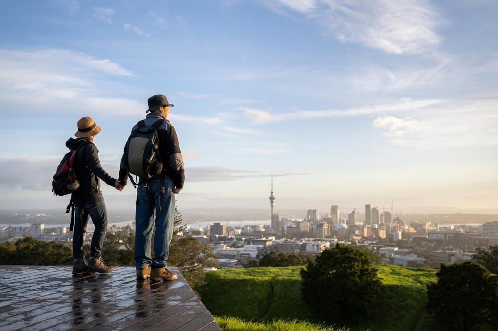 couple of hikers enjoying the panoramic views of Auckland in winter with a dense fog covering the city