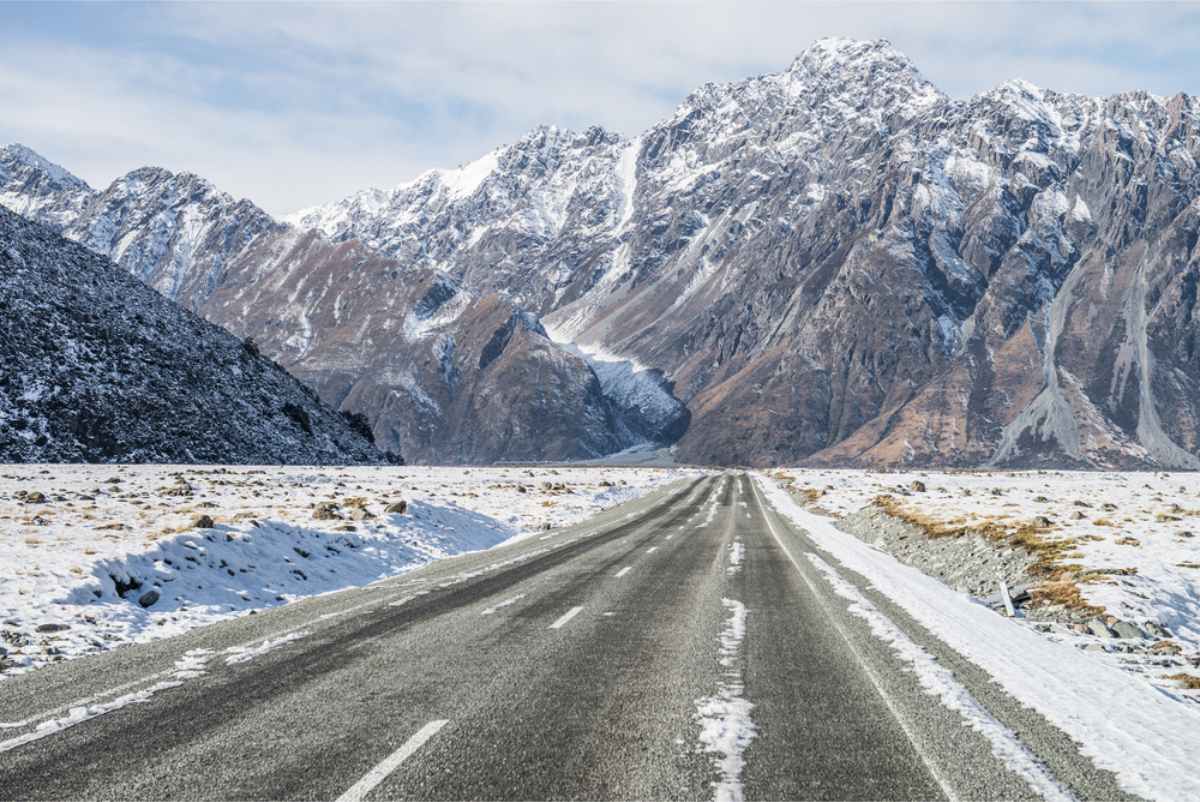 Winter road covered in snow taking to a mountain range