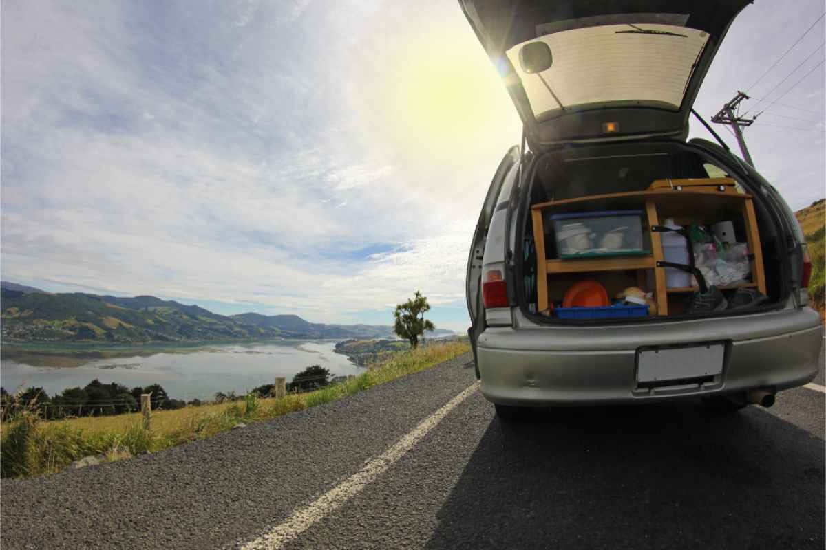Rearview of a campervan parked by a beautiful landscape in NZ