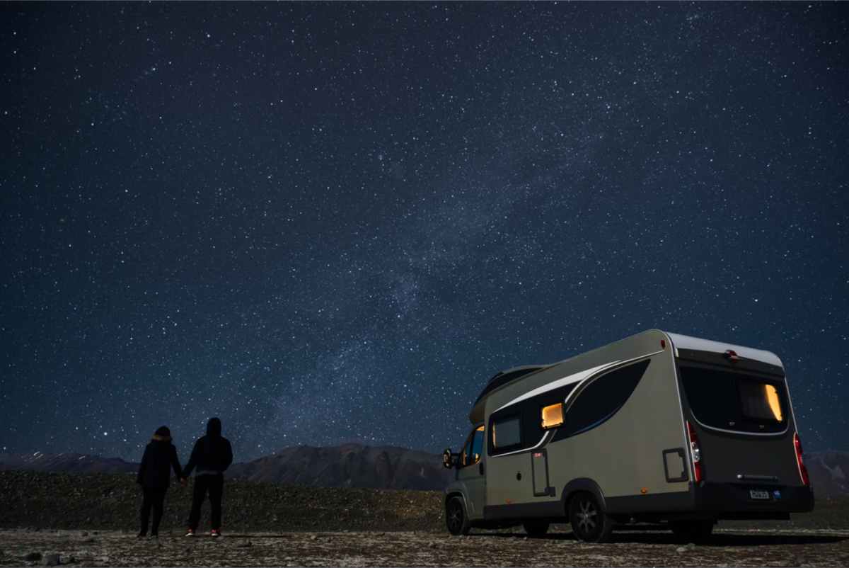 Campers enjoying the starry sky while standing by their motorhome